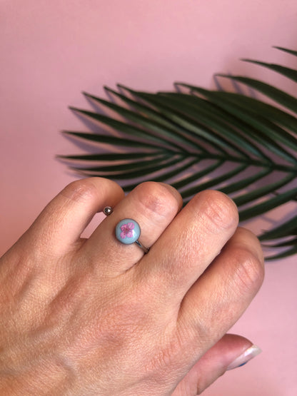 bague résine bleue clair dans laquelle est incrustée un pétale d’alysse